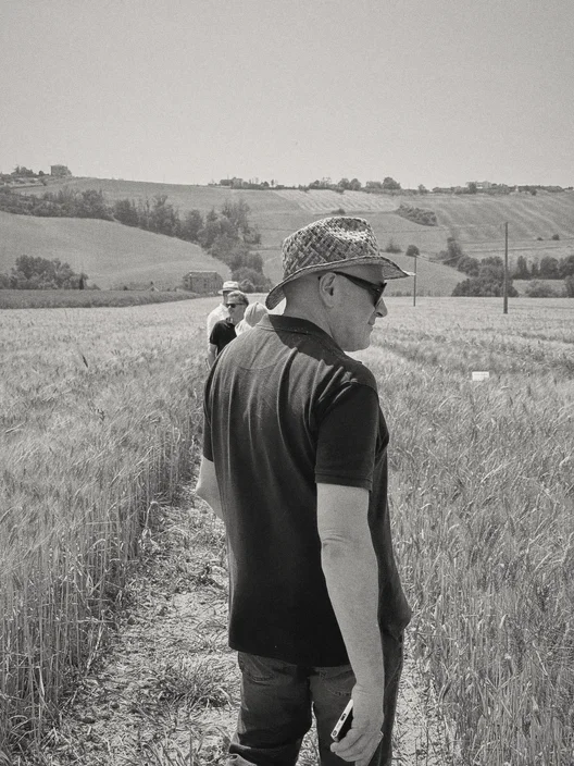 Gabriele Micozzi con il cappello di paglia in un campo di grano, le colline sullo sfondo