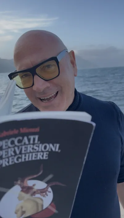 Gabriele Micozzi in barca al tramonto con in mano Peccati, Perversioni, Preghiere