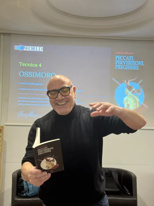 Gabriele Micozzi mostra una copia di Peccati, Perversioni, Preghiere durante una lezione
