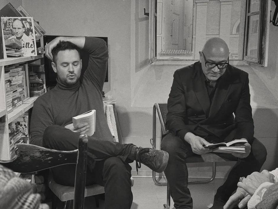 Gabriele Micozzi e un altro lettore seduti con i libri aperti durante una presentazione in libreria