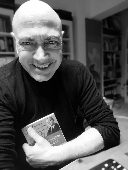 Gabriele Micozzi sorride tenendo in mano una copia di Volo di notte di Saint-Exupéry