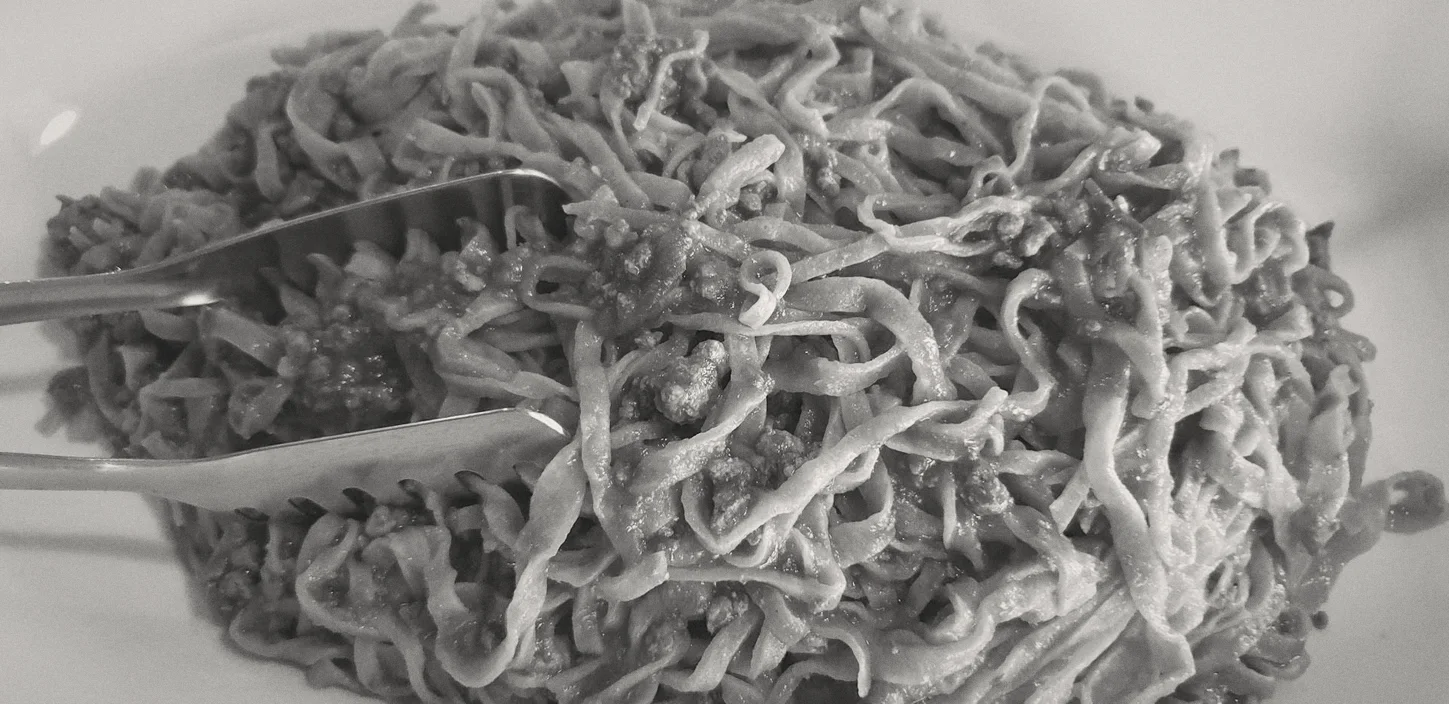 Un piatto di tagliatelle al ragù, la forchetta già dentro